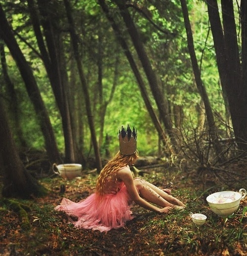 девушка в розовом платье с короной сидит на тропинке в парке