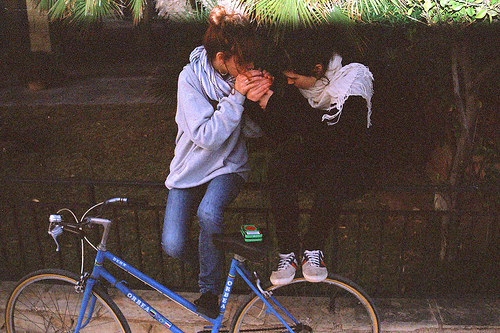 подружки в шарфах сидят под пальмой с велосипедом