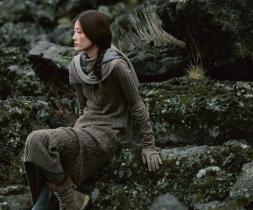 девушка в теплой одежде сидит на камнях укрытых мхом