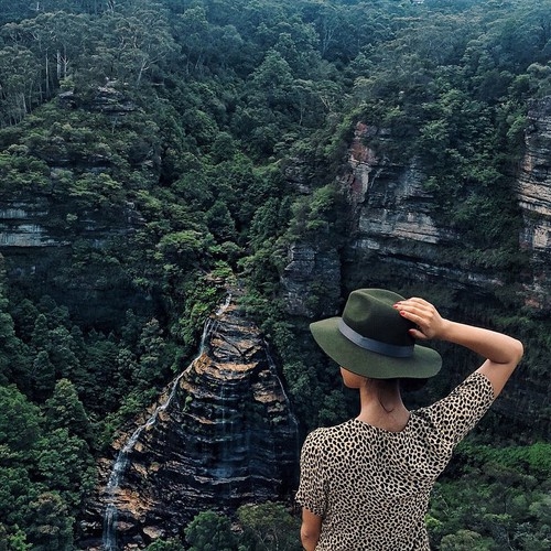 девушка в шляпе со спины на вершине каменных гор