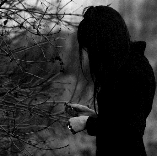 девушка в черном возле веток в темноте