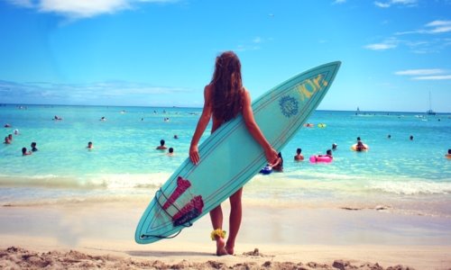 фото девушки на пляже со спины с доской для серфинга летом