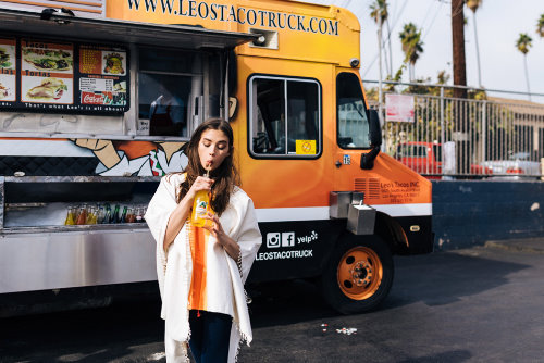 девушка возле желтого грузовика пьет цитрусовый фреш через трубочку веселое фото
