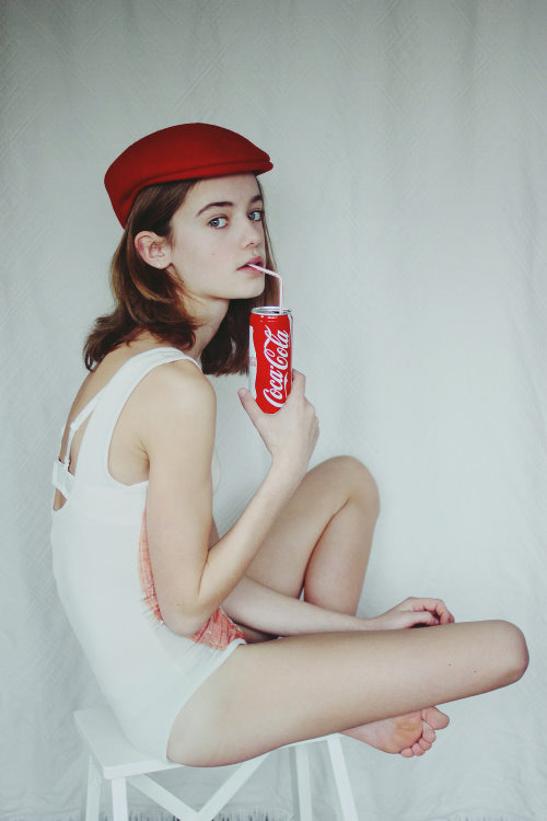 девушка в белом купальнике в красной кепке пьет через соломинку