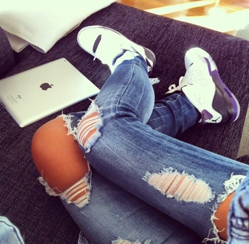 девушка в рваных джинсах лежит на диване с планшетом ipad apple