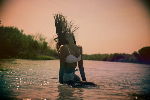 девушка в белом купальнике купается в реке