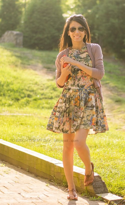 девушка с клатчем в цветочном платье и солнечных очках