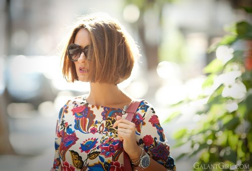 девушка в очках с каре в платье с цветочным принтом в городе летом