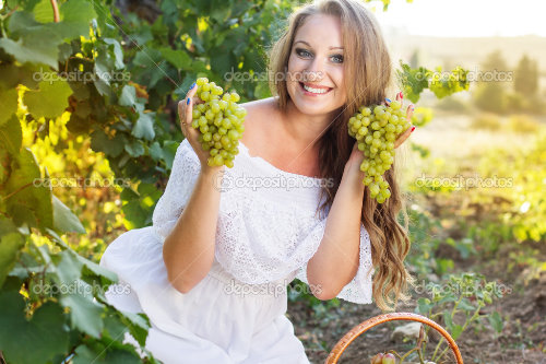 девушка в белом платье с двумя гроздьями винограда в руках