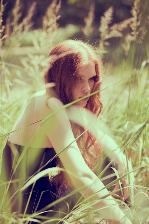 рыжая девушка с прямым пробором сидит в траве