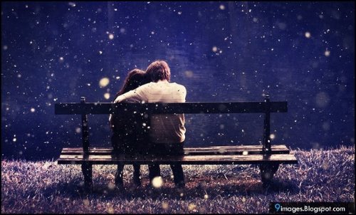 влюбленные подростки сидят спиной н скамейке под снегом
