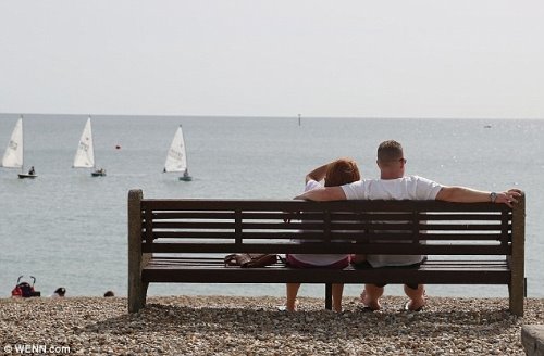 влюбленные любуются парусниками со скамейки на берегу