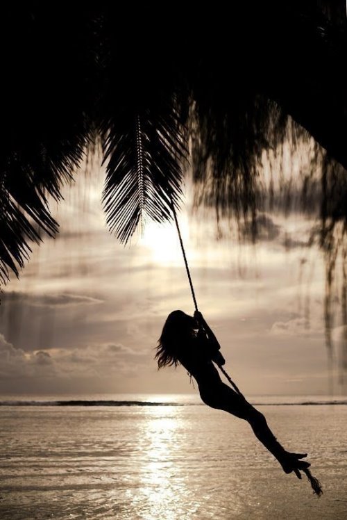 силуэт девушки которая катается на тарзанке под пальмами