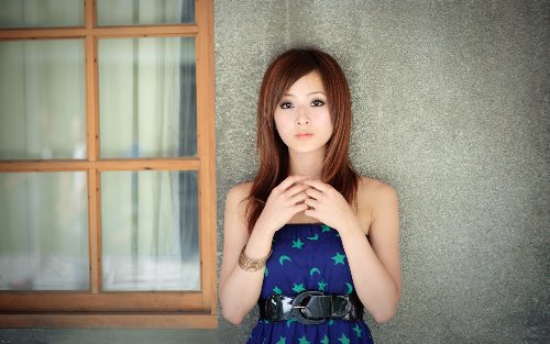 девушка в синем платье стоит под домом у окна