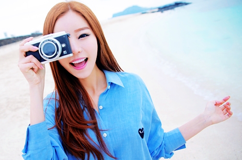 девушка с фотоаппаратом на берегу моря широко улыбается