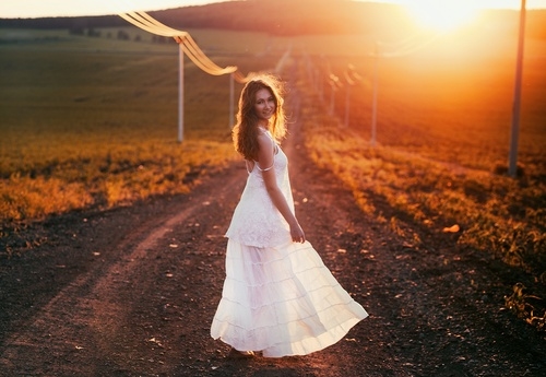 девушка в белом платье идет вдоль дороги светит уходящее солнце