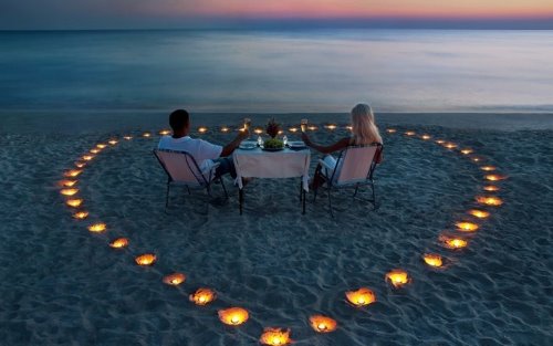 романтический ужин на берегу моря вечером с пляжем украшенным свечами