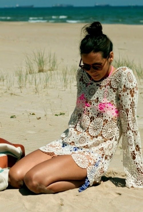 девушка в платье сетке сидит на берегу моря