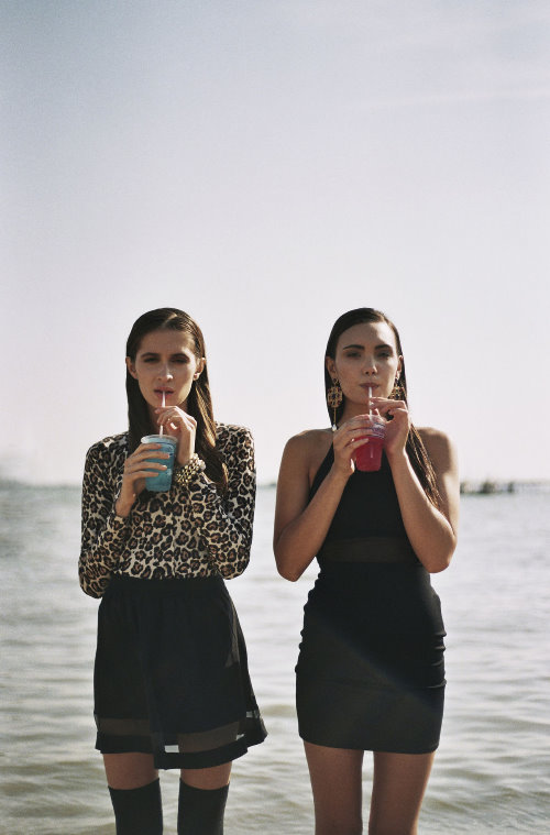 две девушки пьют через соломинку коктейль стоя в воде