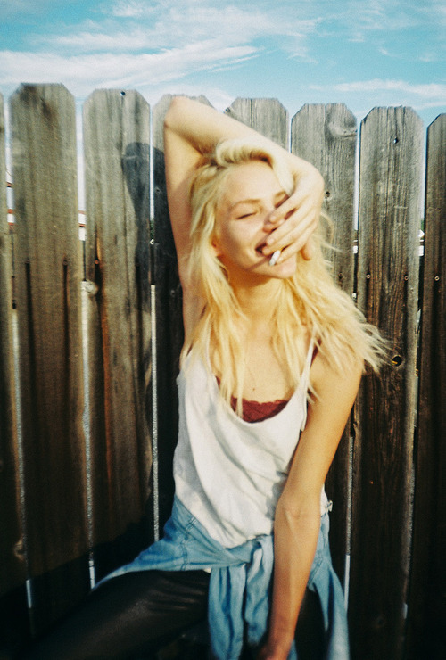 блондинка с сигаретой под забором
