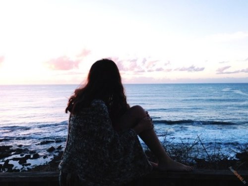 романтическая девушка со спины на закате на берегу моря