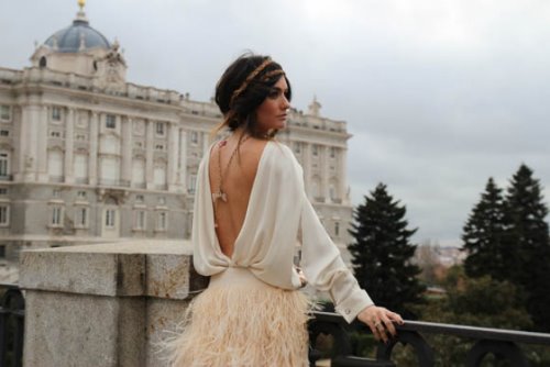 девушка на территории замка со спины в красивом платье с открытой спиной и юбке из перьев