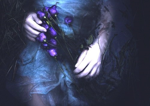 девушка лежит в воде на животе у неё букет из фиолетовых цветов мрачное фото