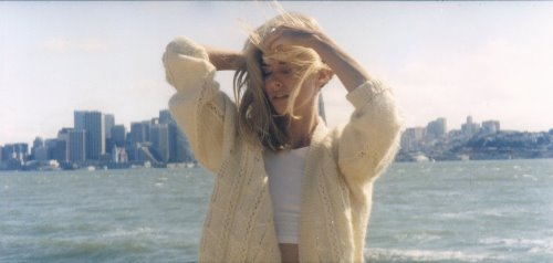 блондинка в пуловере на фоне моря