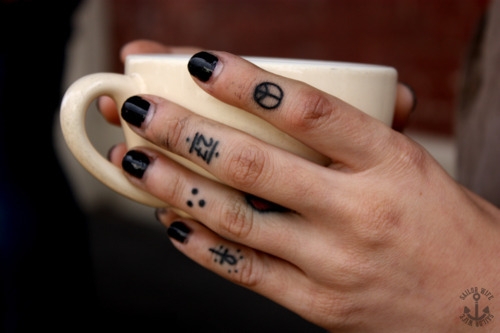 девушка с черными ногтями татуированными пальцами держит кружку