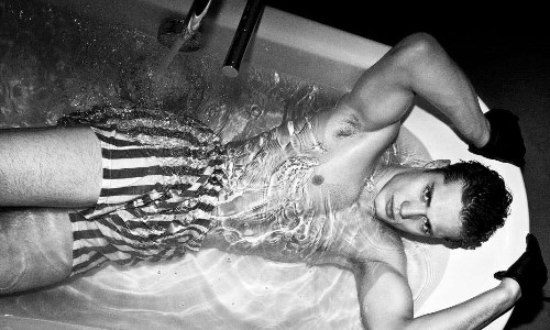 красивых парень в полосатых шортах лежит в ванной