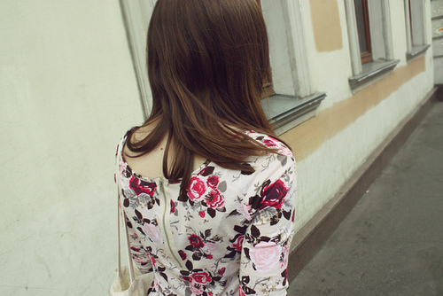 Девушка с коричневыми волосами гуляет по городу в платье в цветочек