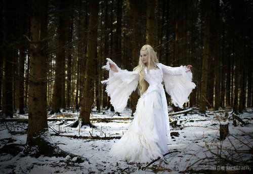 изумительная девушка в праздничном белом платье в лесу со снегом