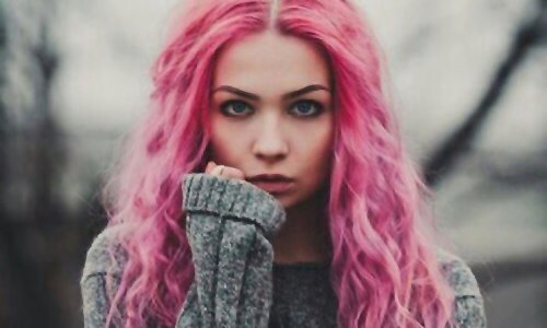 красивая девушка в сером свитере с розовыми вьющимися волосами и синими глазами