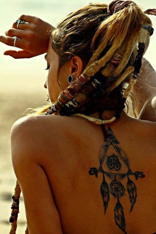Девушка с дредами в хвосте и татуировкой в виде ловца снов на спине.