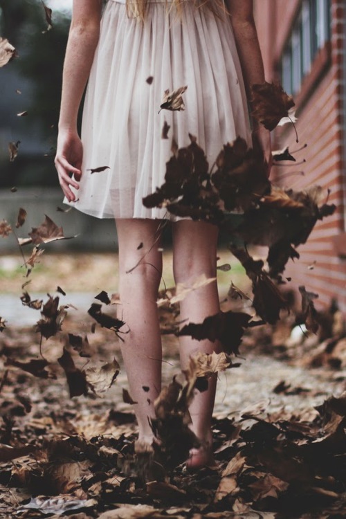 босые ноги в легком плате по колено стоят в коричневых листьях