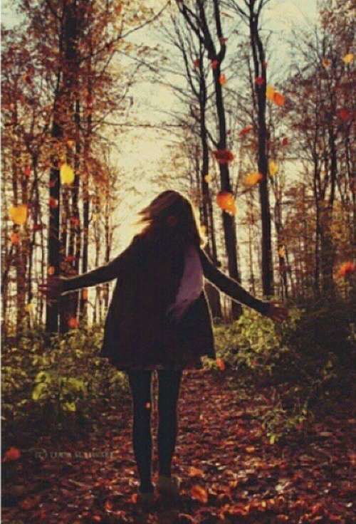 девушка в тёплой одежде кружит в лесу вместе с листопадом