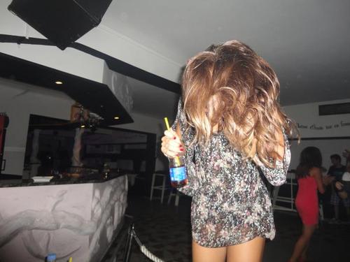 девушка с напитком в руках прыгает в клубе