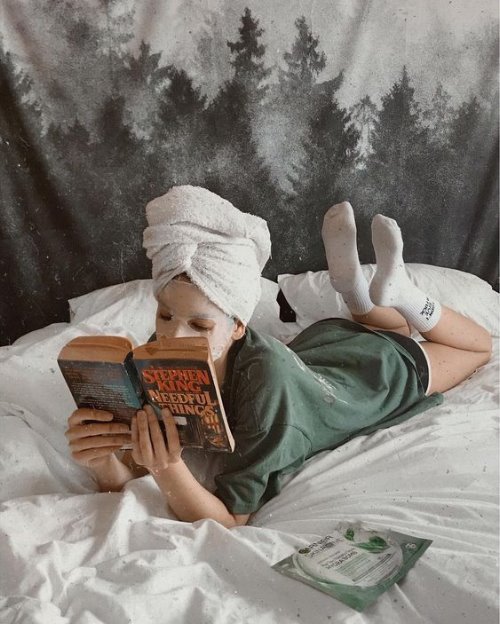 Девушка читает книгу с маской на лице