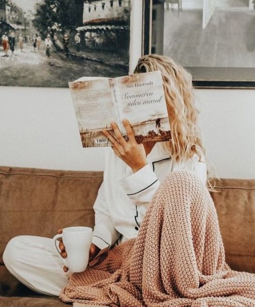 Девушка под вязаным пледом читает книгу прикрыв лицо