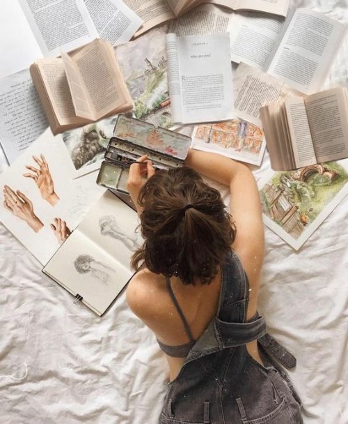 Девушка лежа на животе изучает литературу по рисованию