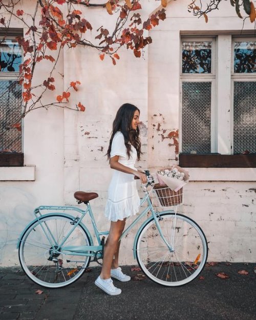 Девушка с велосипедом на фоне дома