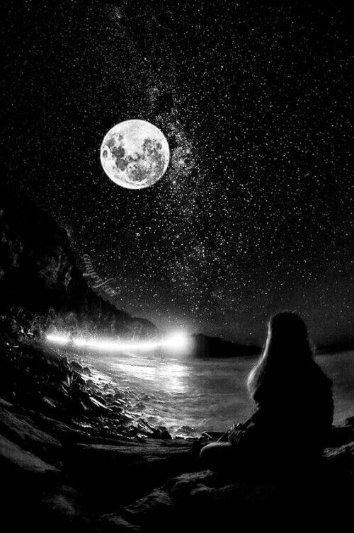 Девушка сидит на берегу и смотрит в небо на звезды и полную круглую луну