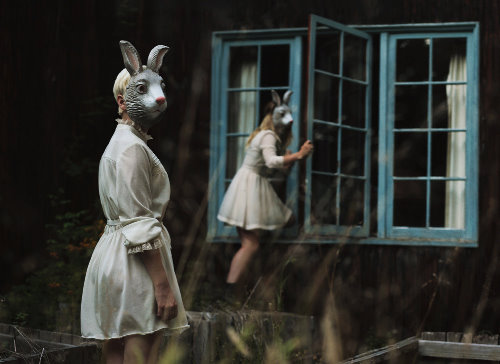 Две девушки в темном лесу пробираются в дом в белых платьях и масках кролика