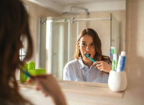 Девушка в мужской рубашке чистит зубы