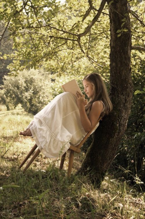 Девушка на деревянном стуле под деревом
