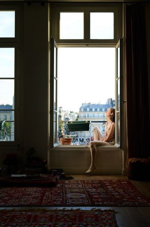 Девушка сидит на окне с пустыми вазонами