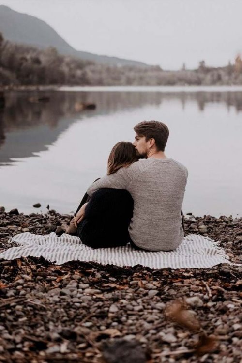 Парень целует девушку в висок на берегу озера