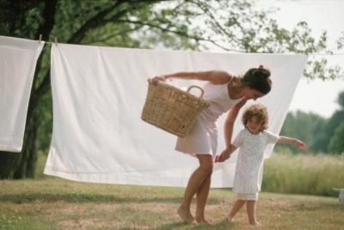 Девушка с дочкой и корзиной белья на улице летом