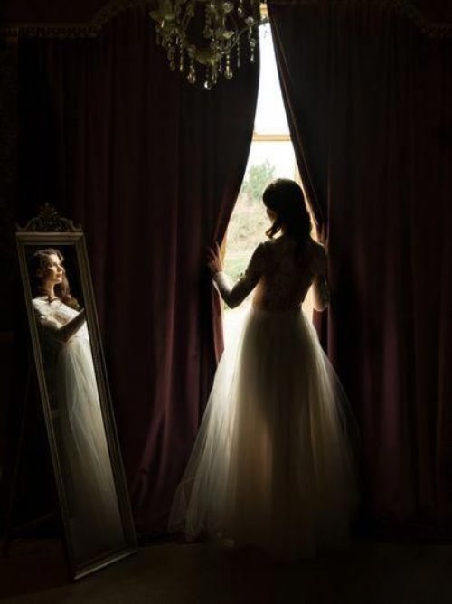Невеста выглядывает в окно раскрыв шторы