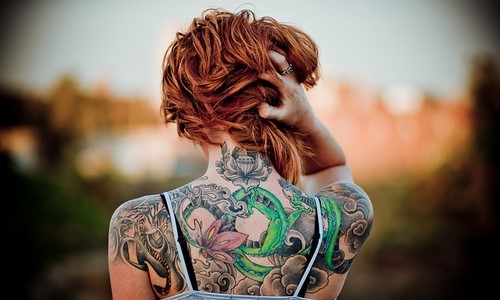 коротковолосая рыжая девушка с татуировками на спине